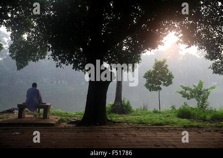 Dhaka, Bangladesh. 21st Oct, 2015. A man sites early in the morning at Ramna park. Ramna park is a large and recreation area situated at the heart of the central Dhaka of Bangladesh on 21 October, 2015. The history of Ramna starts about 1610 CE during Mughal rule, when the city of Dhaka was founded by Subehdar Islam Khan under Emperor Jahangir. At that time two beautiful residential areas were developed in the northern suburb of Dhaka city. This park is one of the most beautiful areas in Dhaka with lots of trees and a lake near its center. ""ªPhoto: Monirul Alam (Credit Image: © Monirul Alam Stock Photo