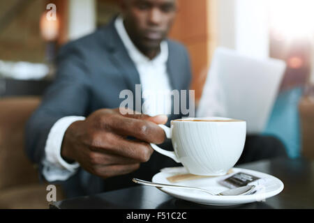 Close up shot of young man 's hand picking up cup of coffee. Businessman sitting at hotel lobby drinking coffee. Stock Photo