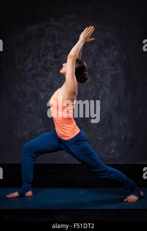 Woman practices yoga asana utthita Virabhadras Stock Photo