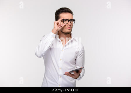 Portrait of a pensive businessman holding tablet computer and looking away isolated on a white background Stock Photo