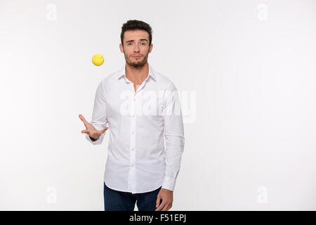 Portrait of a handsome man throwing tennis ball isolated on a white background Stock Photo