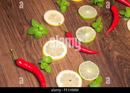 Chili, between lemons, limes and mints, on wooden background Stock Photo