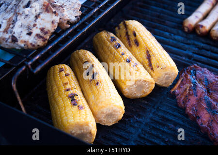 Grilling yellow sweet corn, on a babeque. Near sausages and meat Stock Photo