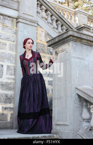 portrait of a beautiful red haired girl wearing Gothic inspired Victorian era clothes. vampire or historical romance era. Stock Photo