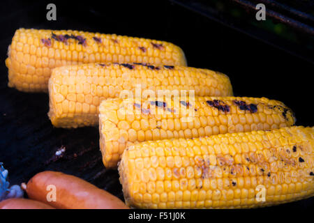 Grilling yellow corn, near sausages, on a gas barbeque Stock Photo
