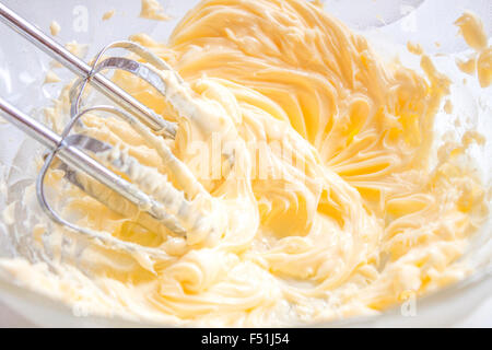 Whisking butter, in a bowl full of butter and egg yolks Stock Photo