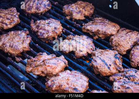Grilling minced meat steaks, on a gas barbeque Stock Photo