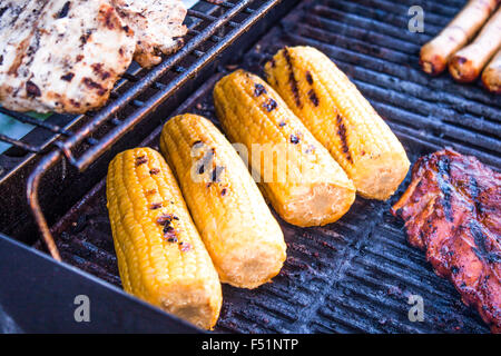 Grilling yellow sweet corn, on a babeque. Near sausages and meat Stock Photo