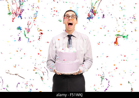 Studio shot of a delighted man holding a birthday cake and looking at the confetti streamers flying around him Stock Photo