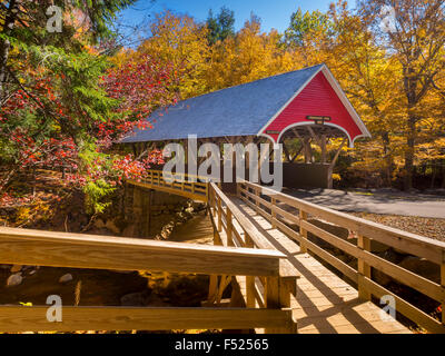Red covered bridge in Fanconia New Hampshire during Fall season Stock Photo
