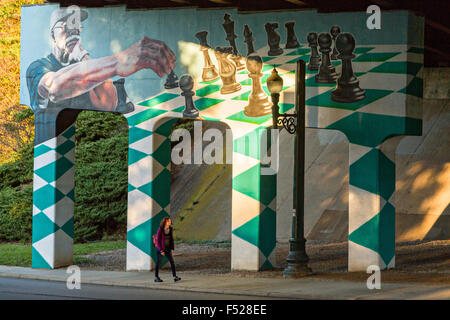 A woman walks past the Asheville Mural Project painted on the overpass under Highway 240 Bridge connecting Lexington and Broadway in Asheville, North Carolina. Stock Photo