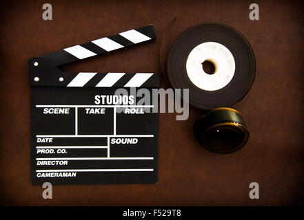 Movie clapper board and 35 mm film reels detail on brown table Stock Photo