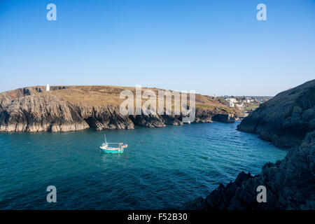 Porthgain mouth of entrance to harbour with lone fishing boat and white beacon tower on cliff opposite Pembrokeshire Wales UK Stock Photo