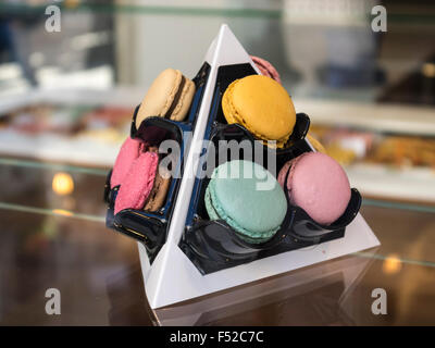 Various macarons in different colors on a tetraeder-shaped display. Stock Photo