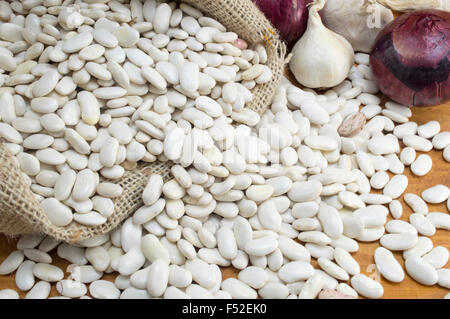 White beans in a bag with garlic and onions on the table Stock Photo