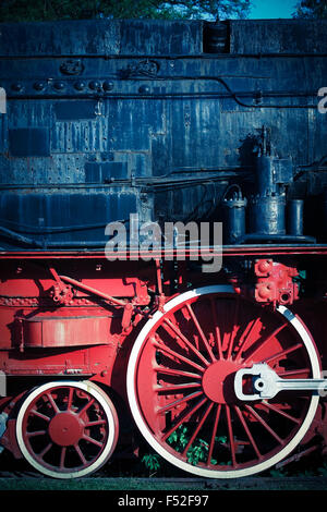 Color image of an abandoned steam locomotive's wheels, with plants ...