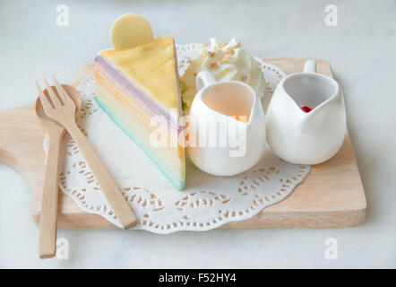 Rainbow crepe cake with sauce on wood plate Stock Photo