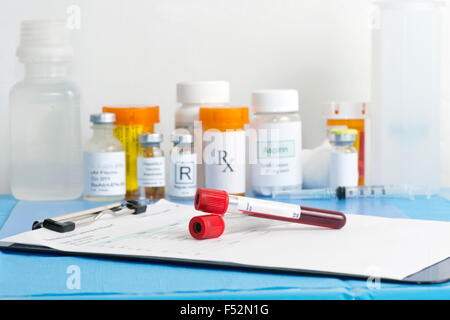 Blood collection sample tubes on patient chart with medical supplies in background. Stock Photo