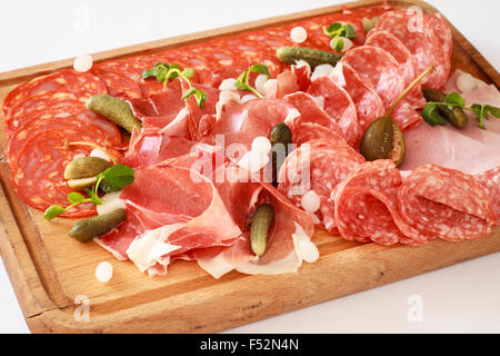 Charcuterie board - A platter of ham & bacon slices with pickles on a wooden board Stock Photo