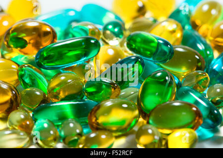 Amber, blue, green, and yellow gelatin capsules form an interesting medical background. Stock Photo