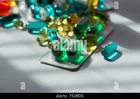 Selection of multi-colored gelatin capsules on sunlit table. Stock Photo