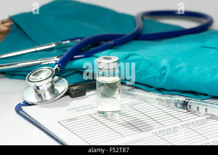 Vial and syringe with stethoscope and scrubs on medical chart. Stock Photo