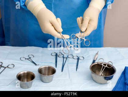 Surgical technician places a selection of instruments on the sterile table. Stock Photo