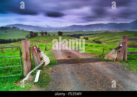 Gravel open road with cattle grid gate across green cultivated fields near Barrington tops in rural NSW Stock Photo