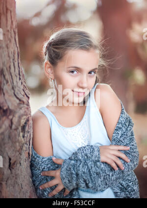 Cute ten-year-old girl posing for the camera sitting at the table ...