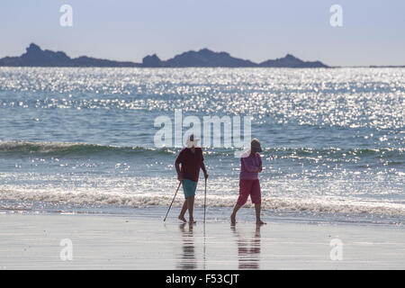 Pensioner couple walking along the sore line St St Ouen's beach Jersey Channel Islands Stock Photo