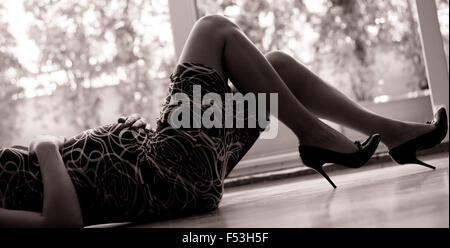 Pregnant woman in hi heels lying on the floor Stock Photo