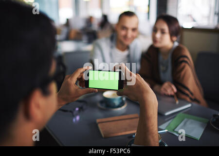 Friend taking photo of young couple on the phone Stock Photo