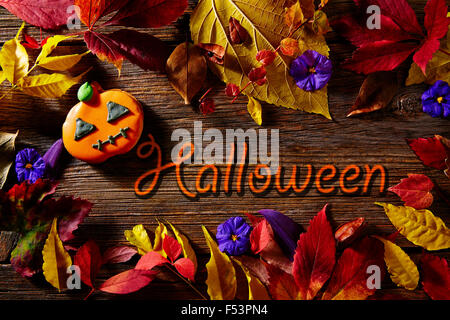 Halloween written word in pumpkin fall background with autumns red golden leaves Stock Photo