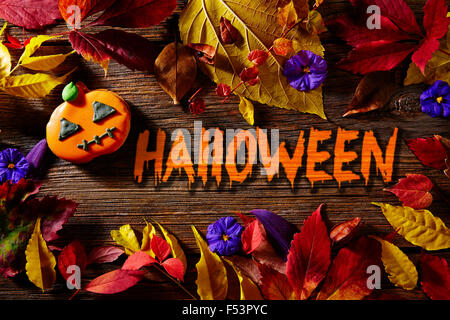 Halloween written word in pumpkin fall background with autumns red golden leaves Stock Photo