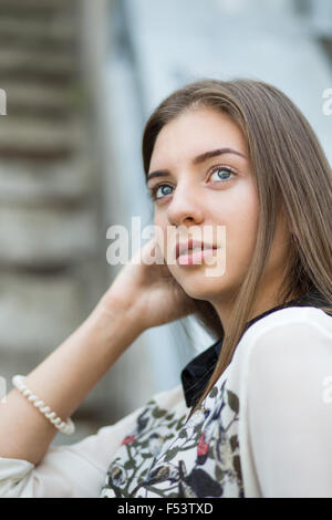 Young student hipster girl looks straight ahead. Portrait of pretty girl with long brown hair Stock Photo