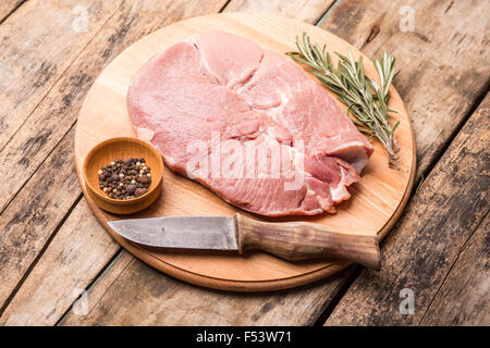 Big chunk of beef with rosemary, pepper and knife on cutting board on wooden background. Menu and meat recipe background Stock Photo