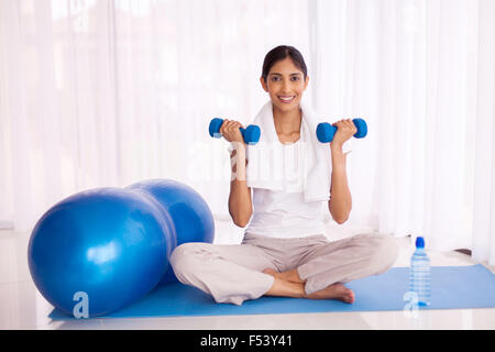 fit Indian girl exercising with dumbbells at home Stock Photo