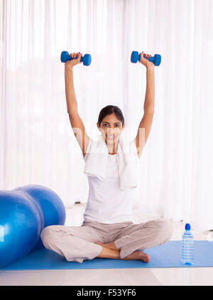 happy healthy young Indian woman lifting dumbbells Stock Photo