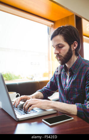Hipster student using laptop in canteen Stock Photo