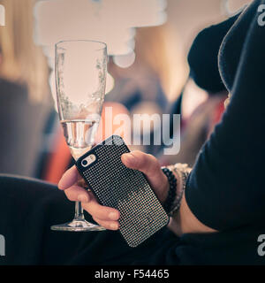 Person holding a smartphone and having a glass of white wine in a restaurant in Reykjavik, Iceland Stock Photo