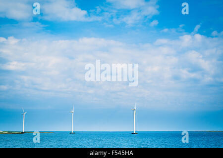 Windmills on a row in the blue ocean Stock Photo