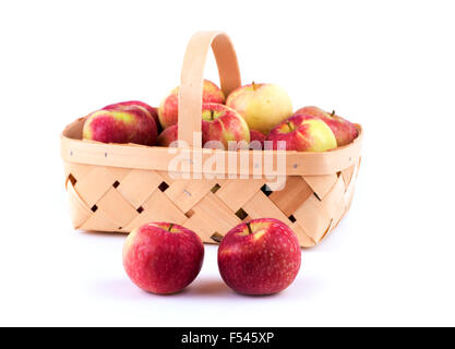 Two apples in front of a wooden basket loaded with more apples, on white Stock Photo
