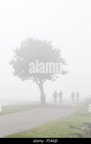 Two couples walking along a path in fog, Scotland, UK Stock Photo