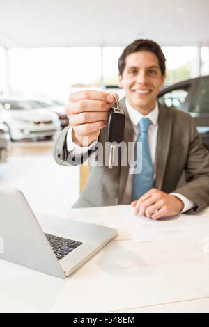 Young salesman holding car key on white background Stock Photo - Alamy