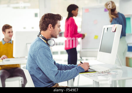 Graphic designer wearing headphones at desk Stock Photo