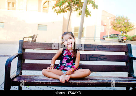 Funny cute little girl sticking out her tongue (sunset lighting) Stock Photo