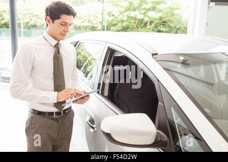 Smiling salesman using tablet near a car Stock Photo