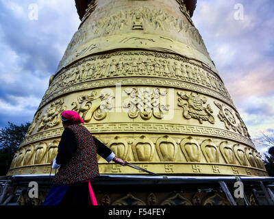 Woman in traditional Tibetan clothes turning a prayer wheel in Shangri-La in China Stock Photo