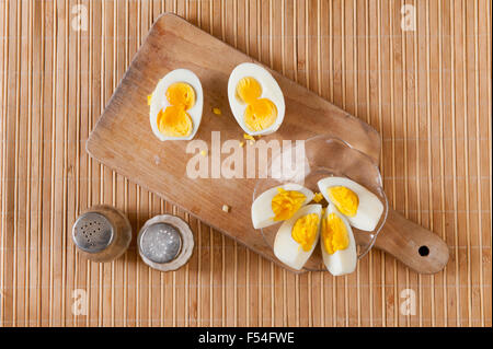 Cut boiled two yolks egg with salt and pepper, double yolked and one yolk eggs comparison rare situation, food lying on old wood Stock Photo