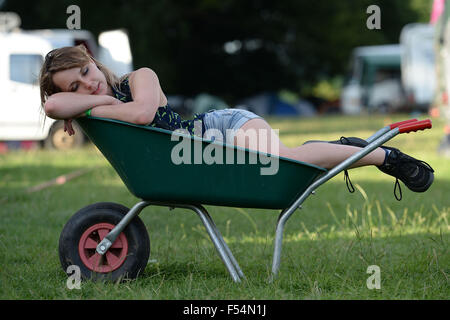 A teenage girl sleeps in a green wheelbarrow at Croissant Neuf festival in Usk, South Wales. Stock Photo